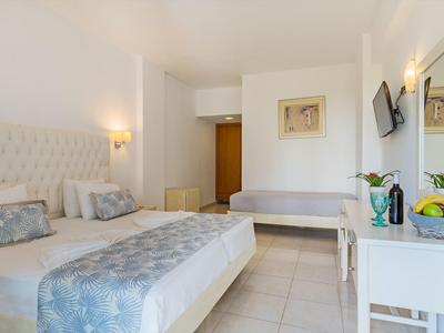 Hell eingerichtetes Hotelzimmer mit Doppelbett, Sofa, TV und Schreibtisch.