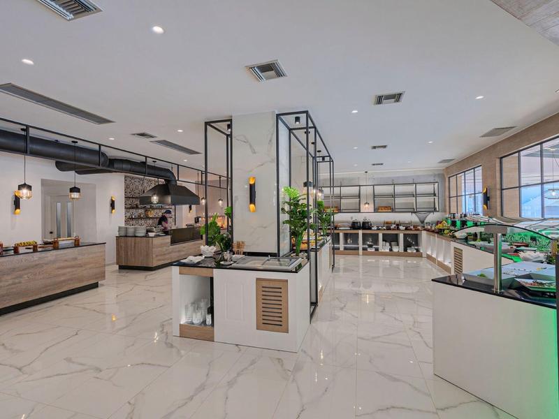 Großer, moderner Verkaufsraum mit hellen Fliesen, vielen Pflanzen und Glasvitrinen.