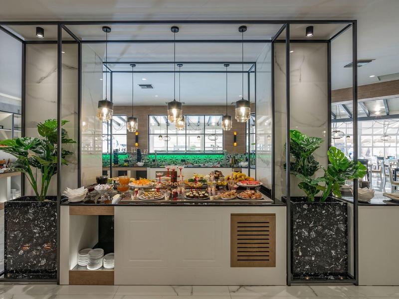 Moderne Theke mit Snacks, Pflanzen und Glaswänden in hellem, großzügigem Raum.