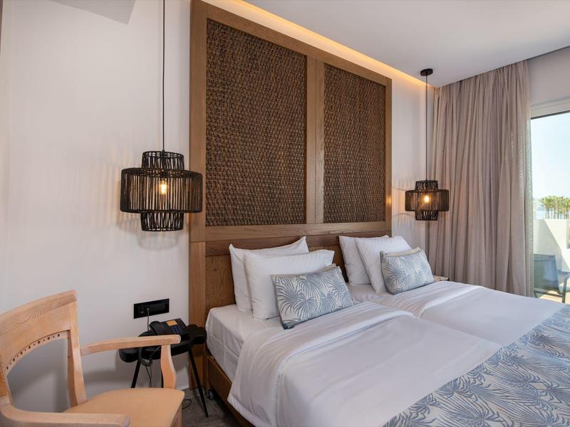 Modernes Hotelzimmer mit Doppelbett, Holzvertäfelung und zwei dekorativen Lampen an der Wand.