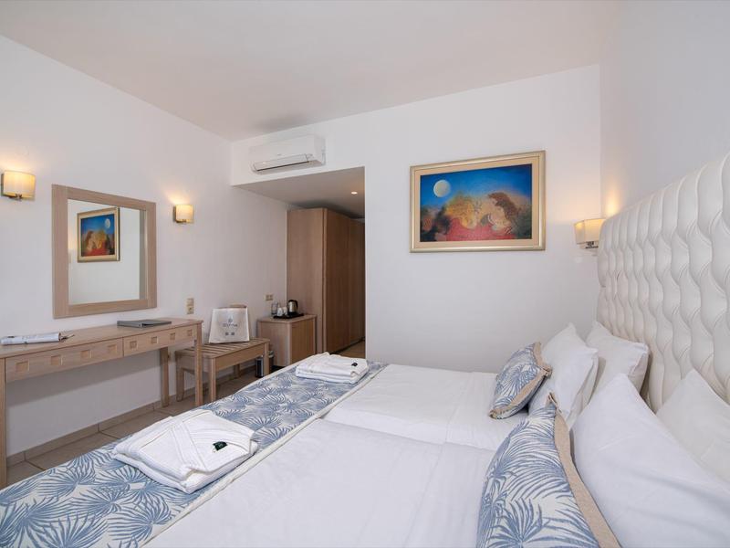 Modernes Hotelzimmer mit zwei Betten, Schreibtisch, Spiegel und Kunst an der Wand.