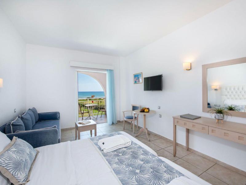 Helle Hotelzimmer mit Doppelbett, Sofa, Schreibtisch und Balkon mit Blick ins Freie.