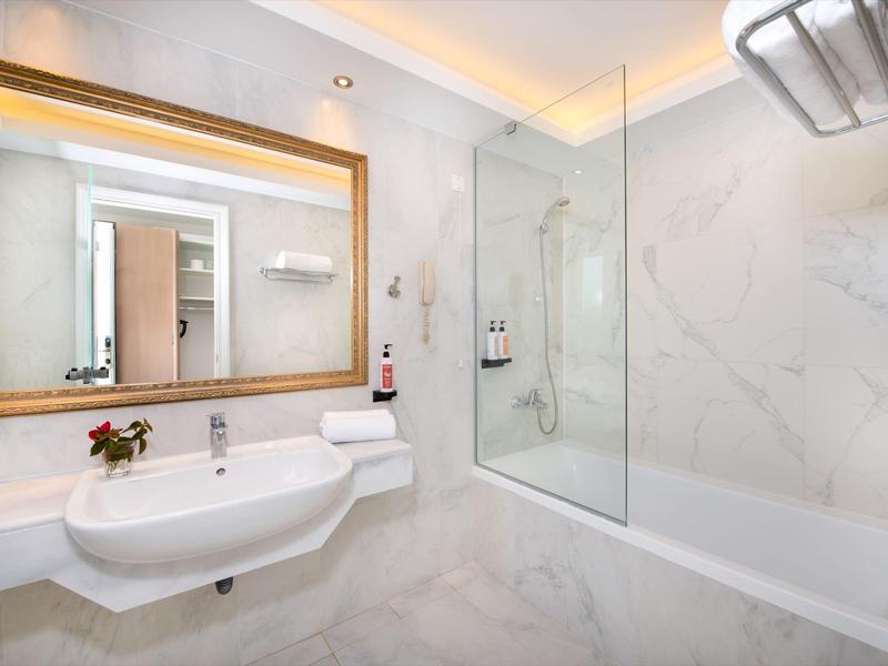 Modernes Badezimmer mit weißer Badewanne, Waschbecken und großem Spiegel mit Holzrahmen.