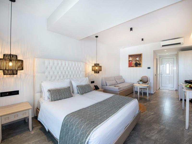 Modernes Hotelzimmer mit Doppelbett, grauen Akzenten und gemütlicher Sitzecke.