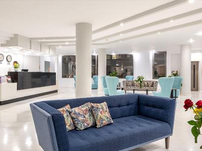 Moderní hotelová lobby s modrou pohovkou, recepcí a stylovým osvětlením.