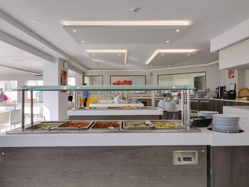 Strefa bufetu w nowoczesnej restauracji hotelowej z różnymi potrawami pod szklaną osłoną.