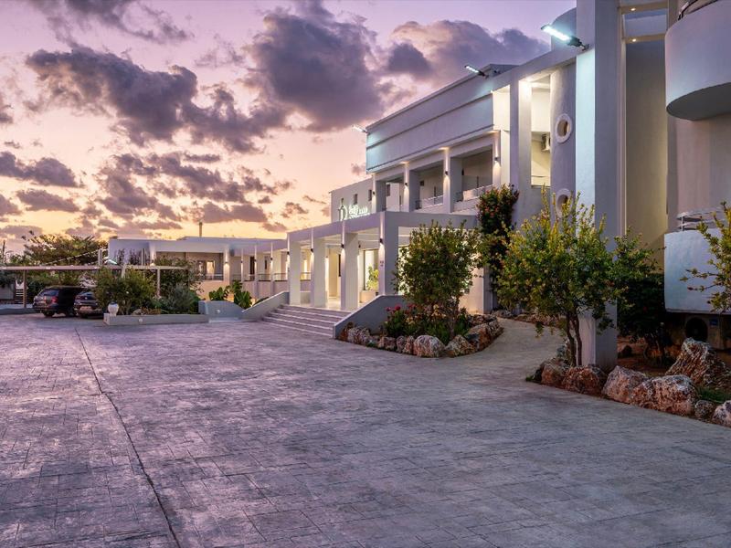 Nowoczesny kompleks hotelowy o zachodzie słońca z szerokim chodnikiem i zagospodarowanymi klombami.