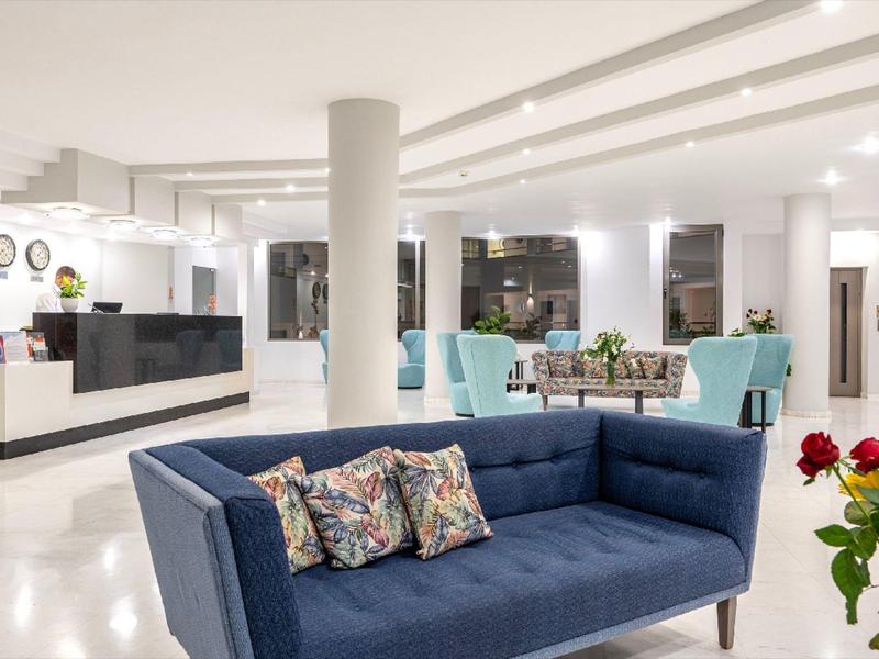 Jasna lobby hotelowa z nowoczesnym wnętrzem i niebieską sofą na pierwszym planie.