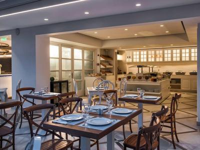 Modern restaurant with set wooden tables and open kitchen area.