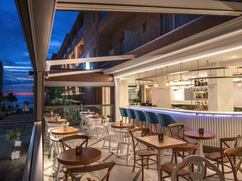 Modern outdoor bar area with wooden tables and chairs at dusk.