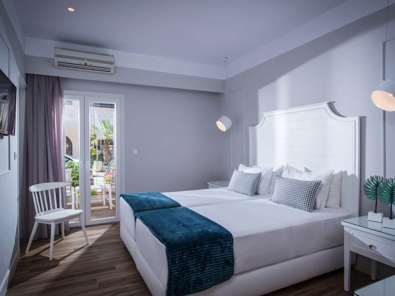 Modern hotel room with double bed, white headboard, and balcony access.