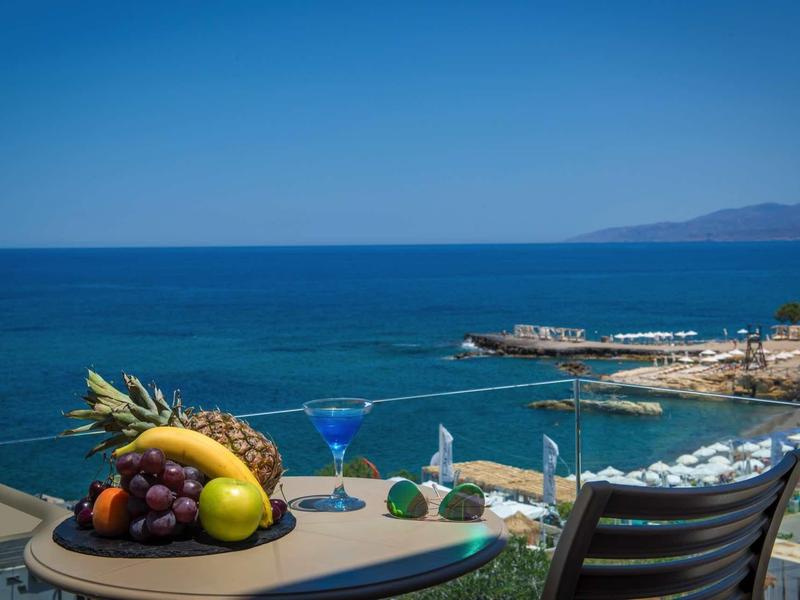 Sea view with table, fruit bowl, and cocktail on a hotel terrace.
