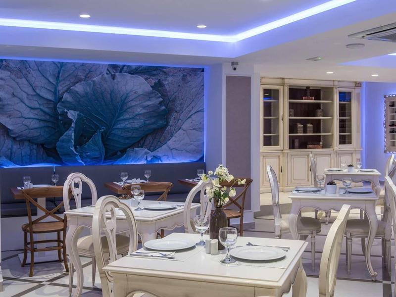 Elegant restaurant with white furniture and large blue flower artwork on the wall.