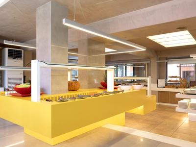 Moderní hotelový bufet se žlutým bufetem a světlým, otevřeným jídelním prostorem.