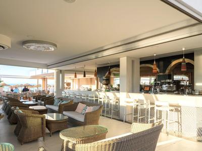 Otevřený hotelový bar s moderním zařízením a výhledem na terasu.