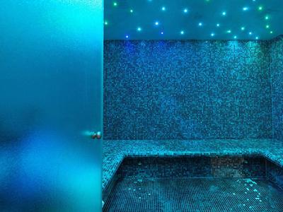 Interiér moderní spa oblasti s bazénem a atmosférickým modrým osvětlením.