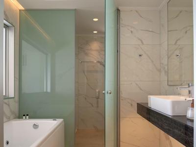 Moderní koupelna s vanou, skleněným sprchovým koutem a umyvadlem na černé desce.