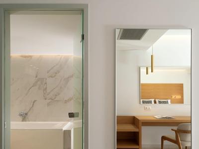 Moderní hotelová koupelna s mramorovou stěnou a přilehlým pokojem se zrcadlem a dřevěnými detaily