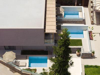 Vista desde arriba de un hotel moderno con piscina privada y sombrilla en una terraza.