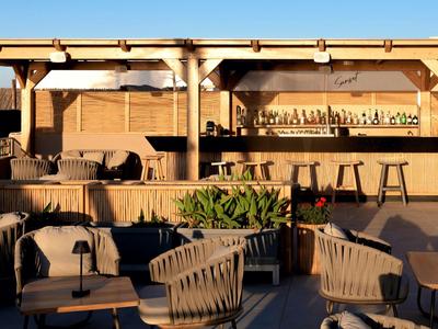 Area bar all'aperto con mobili in legno e sedie alla luce calda della sera