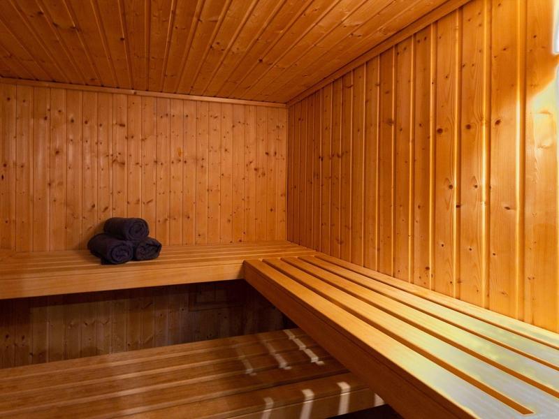 Dřevěná sauna s lavicemi a složenými ručníky v rohu