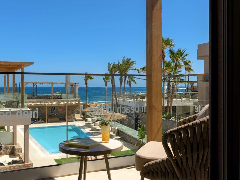 Výhled na bazén a moře z terasy s židlí a stolem.