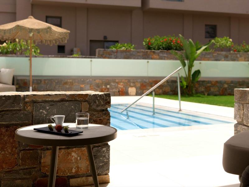 Moderní venkovní prostor s bazénem, posezením a slunečníkem v hotelu.