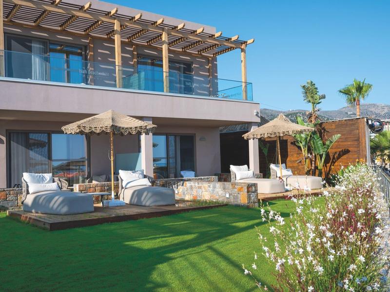 Moderní hotelová zahrada s lehátky, slunečníky a pečlivě udržovaným trávníkem