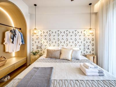 Modernes helles Schlafzimmer mit großem Bett, gemustertem Kopfteil und eingebautem Sitzbereich.