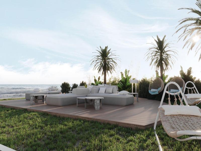 Modern outdoor area with lounge furniture, hanging chairs, and coastal view at sunset.