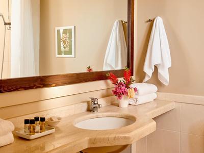 Bagno luminoso con grande specchio, lavabo, asciugamani freschi e fiori sul bancone.