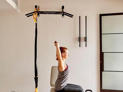 Donna si allena con bande TRX in una sala fitness luminosa con kettlebell.