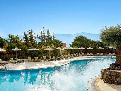 Duży basen hotelowy z leżakami i parasolami pod czystym niebem.