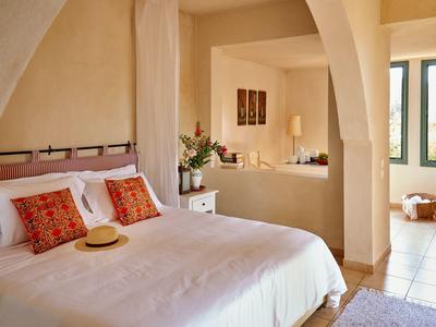 Camera accogliente con letto matrimoniale, cuscini decorativi e vista su un soggiorno luminoso.