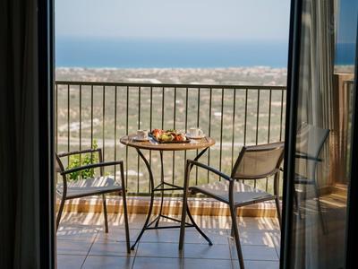 Balcone con tavolo e due sedie, vista sul mare con cielo terso.