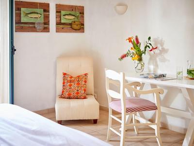 Locale luminoso con tavolo, sedie, poltrona e decorazioni floreali in una camera d'hotel.