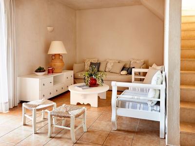 Soggiorno luminoso con zona salotto accogliente, tavolino e vista sulle scale.