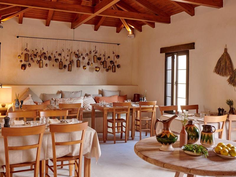 Accogliente sala da pranzo con tavoli, sedie in legno e decorazioni in una casa vacanze.