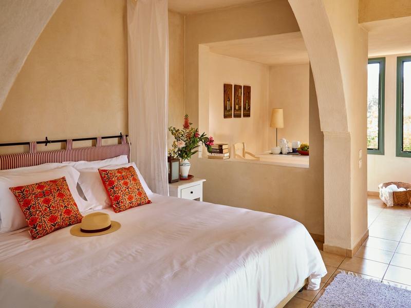 Camera accogliente con letto matrimoniale, cuscini decorativi e vista su un soggiorno luminoso.