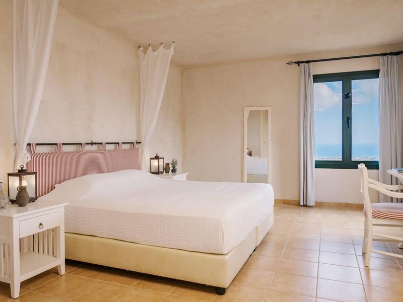 Camera luminosa e semplice con letto grande, finestra e stile minimalista.