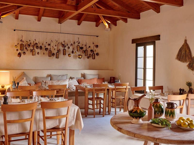 Sala da pranzo accogliente con mobili in legno, tavoli apparecchiati e decorazioni alle pareti.