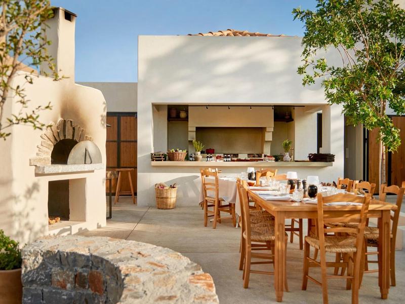 Accogliente area esterna con tavoli, sedie e barbecue in una località soleggiata.