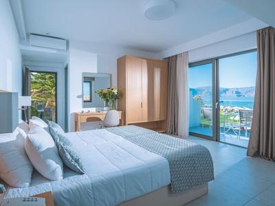 Helles Hotelzimmer mit Doppelbett, großem Fenster und Balkon mit Blick aufs Meer.