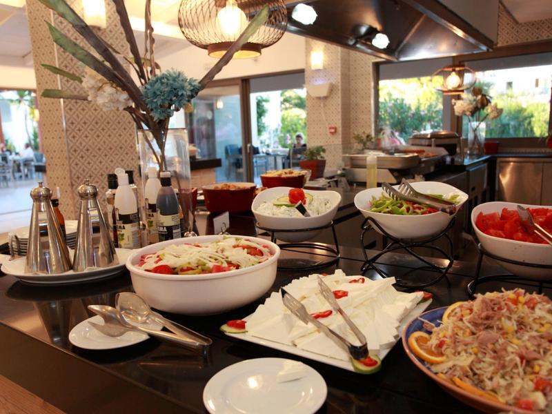 Buffettafel met salades, dressings en kruiden in een goed verlichte restaurantomgeving.