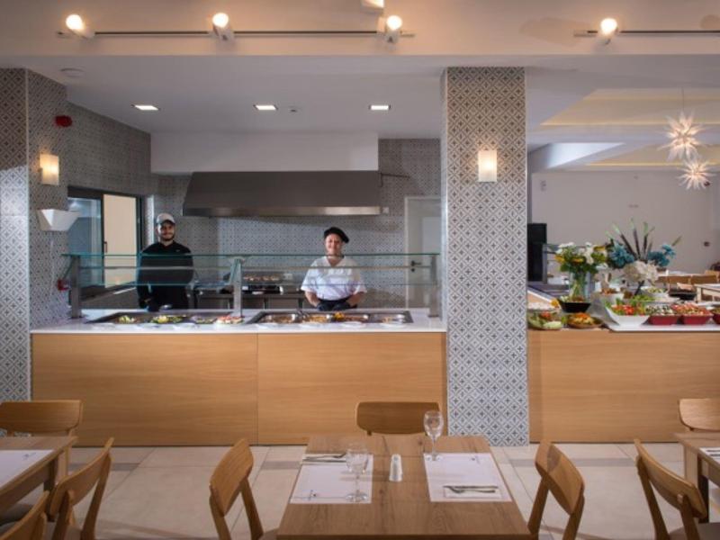 Modern restaurantbuffet met koks achter de balie en houten tafels ervoor