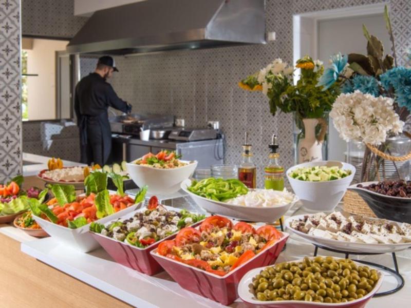 Buffet met verse salades en voorgerechten in een lichte keuken met een kok die kookt.