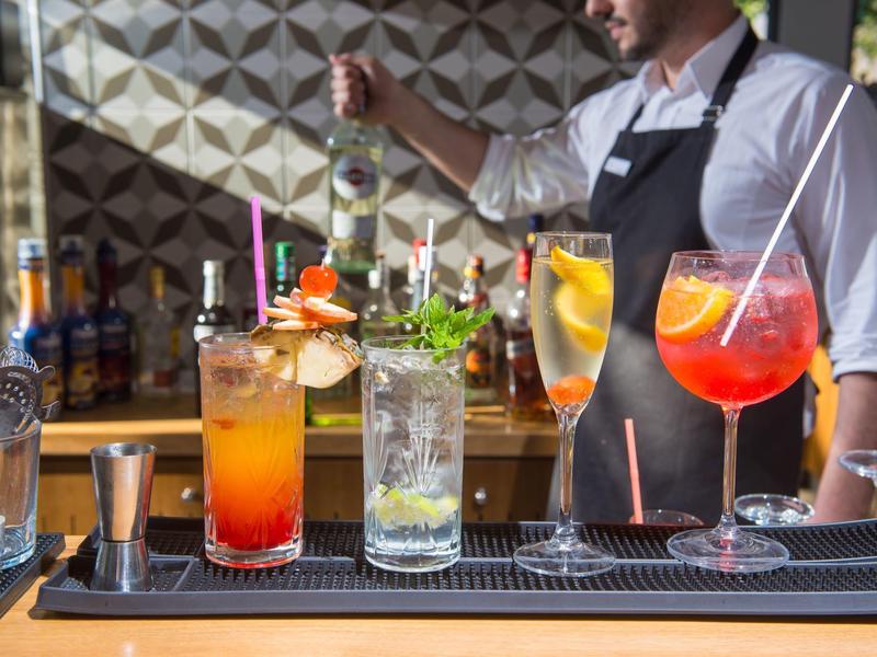 Barkeeper maakt kleurrijke cocktails met ijs en fruit aan de bar klaar.