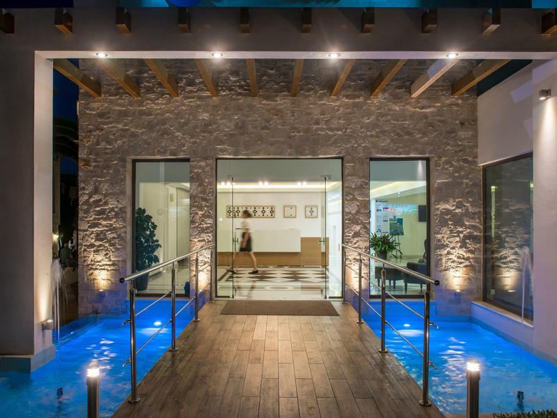 Moderne hotelloper met verlicht waterornament en toegang tot een ruim interieur.