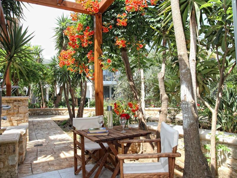 Gezellige buitenruimte met houten meubels en bloeiende planten in een tropische omgeving.