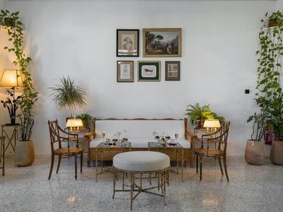 Pohodlný obývací prostor s bílou pohovkou, dřevěnými židlemi, rostlinami a obrazy na zdi.